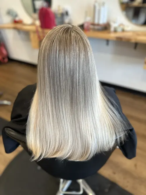Icy platinum blonde with a shadow root on sleek, blunt-cut long hair at Ash and Ivy Salon in Evans, GA